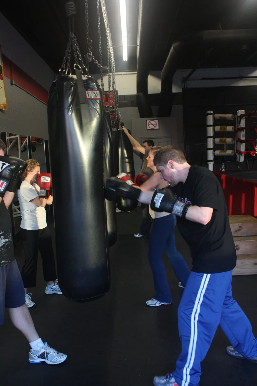 Members working the heavy bags side by side on the gym floor.